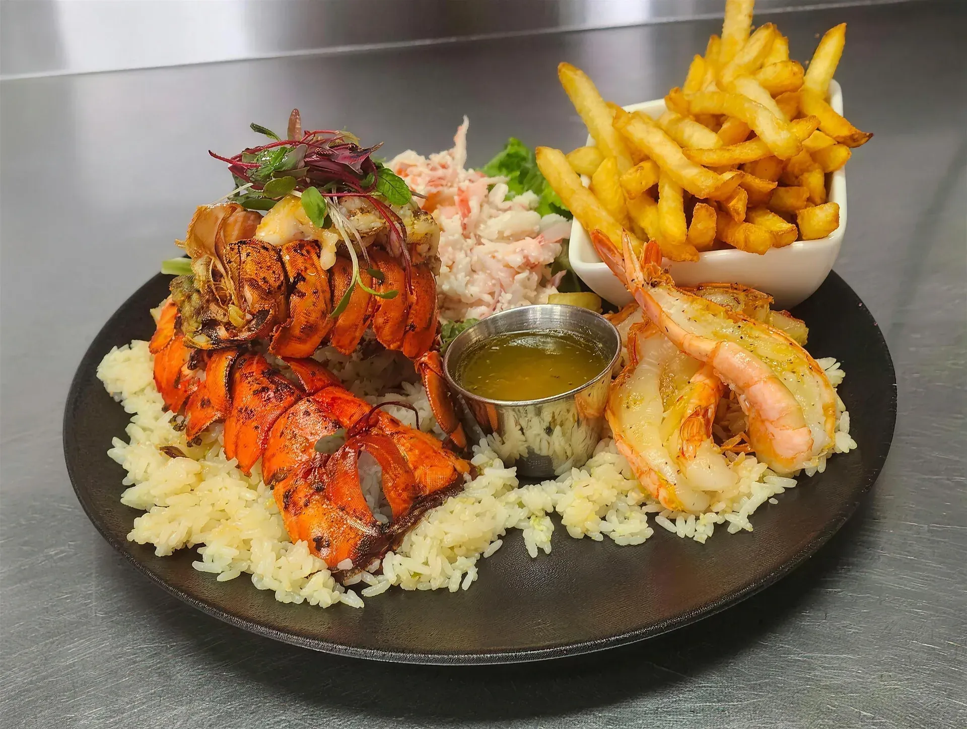 Duo de queues de homard grillées et crevettes papillons sur riz, avec frites et beurre à l'ail
